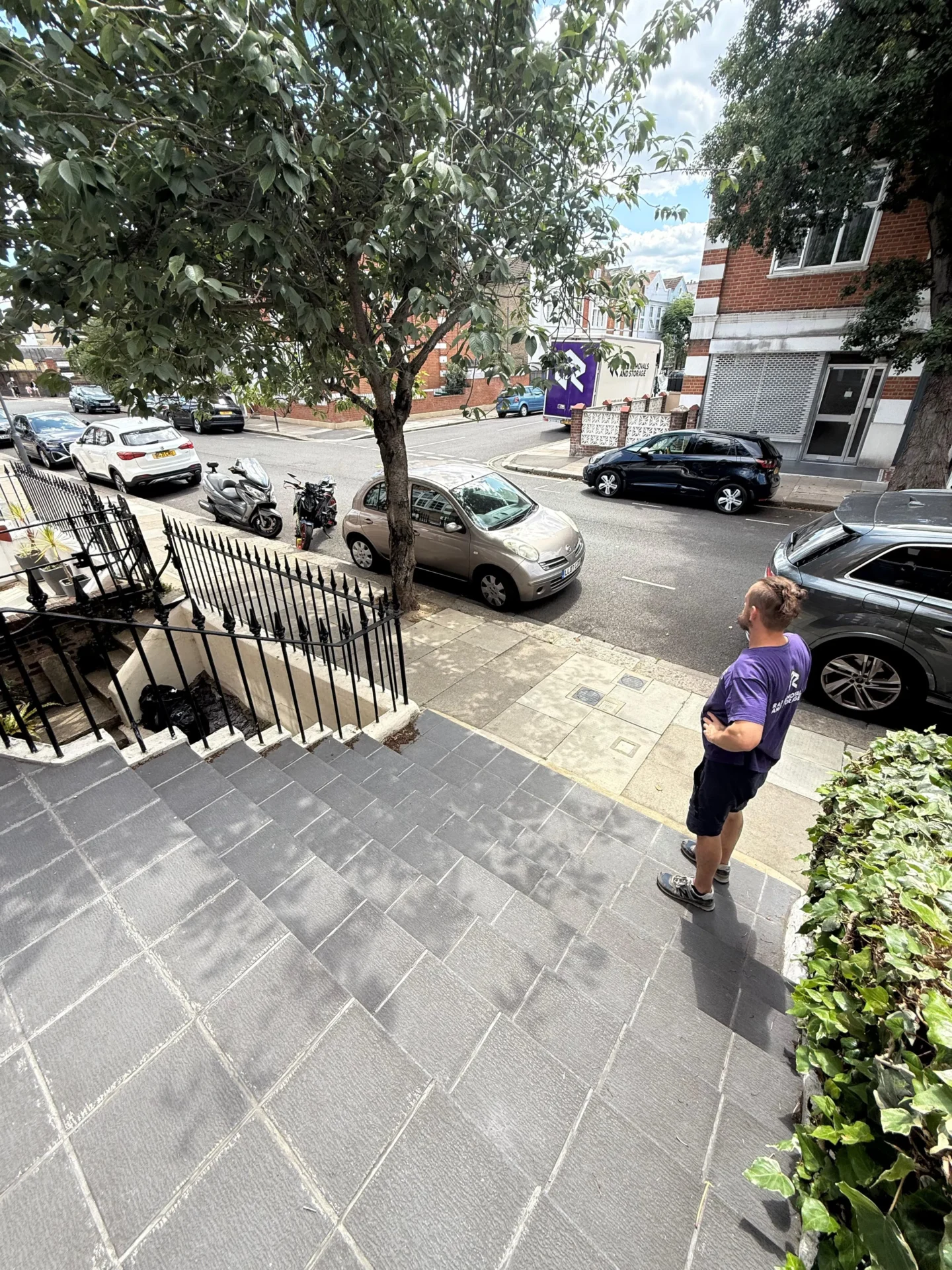 RAD Removals packer standing at the top of stairs in Shepherd’s Bush, looking out for arrival of branded moving van